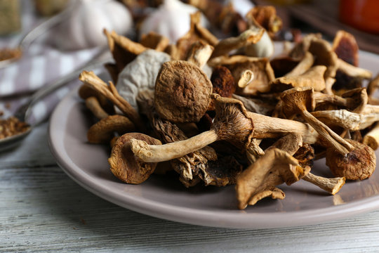 Dried mushrooms in plate on wooden table, closeup