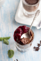 Chocolate panna cotta with chocolate chips and cherry sauce on a blue background