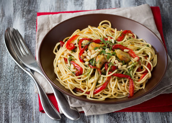 Pasta with baked sweet pepper, garlic, herb oil and pine nuts in a ceramic bowl on the wooden table 