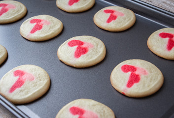 close up horizontal image of a group of freshly baked cookies with red hearts on top  cooling in a cookie sheet