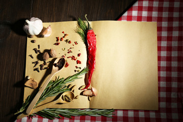 Open recipe book with fresh herbs and spices on wooden background