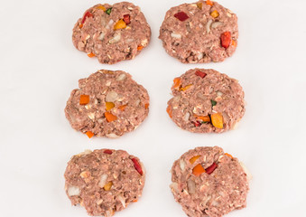 horizontal image of six raw hamburger patties with onion and assorted chopped peppers isolated on white background