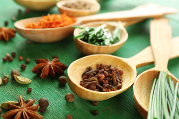 Wooden spoons with fresh herbs and spices on wooden background
