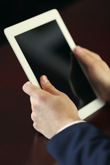 Businessman working with tablet at wooden table, closeup