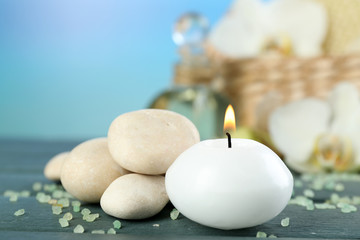 Fototapeta na wymiar Still life with candle, pebbles and spa treatment on wooden table, on bright background