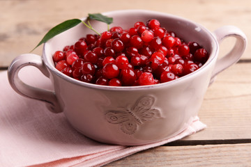 Red currant in bowl on wooden table, closeup
