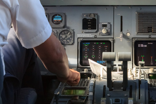 Apilot checking instruments in a plane cockpit