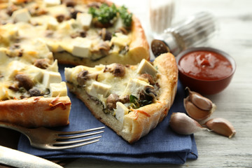 Cheese pie with mushrooms, herbs and sour creme, on napkin, on wooden table background