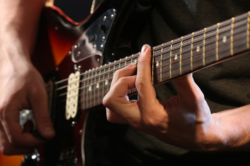 Obraz na płótnie Canvas Young man playing on electric guitar close up