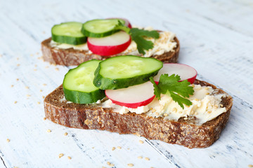 Delicious sandwiches with vegetables and parsley on wooden background