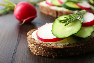 Delicious sandwiches with vegetables and greens on table close up
