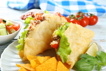 Tasty taco with nachos chips and vegetables on plate on table close up