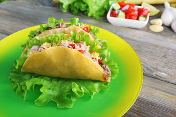 Tasty taco on plate with vegetables on table close up