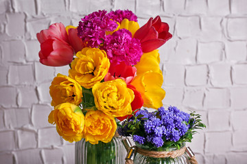 Beautiful flowers in vases on wall background
