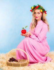 Beautiful young woman in a pink dress sitting in a hay