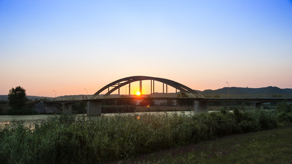 Fototapeta na wymiar Bridge on the river in colourful sunset