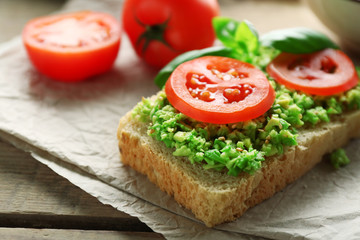 Vegan sandwich with avocado and vegetables on cutting board, on wooden background