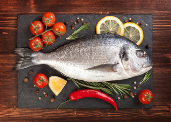 Fresh fish, lemon, spices and tomatoes on a board