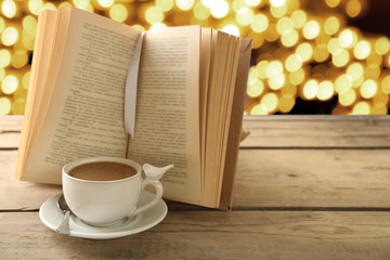 Cup of coffee with open book on bright background