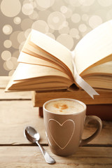 Cup of coffee with open book on bright background