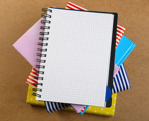 Notebook on top of pile of books and magazines on wooden background