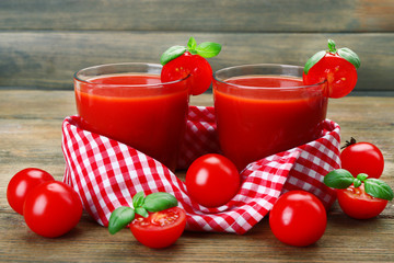 Glasses of tomato juice with vegetables on wooden background