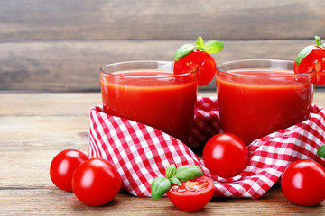 Glasses of tomato juice with vegetables on wooden background