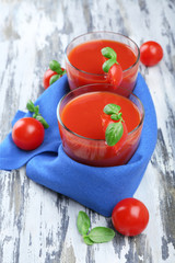 Glasses of tomato juice with vegetables on wooden background