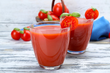 Glasses of tomato juice with vegetables on wooden background
