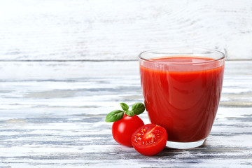 Glass of tomato juice with vegetables on wooden background