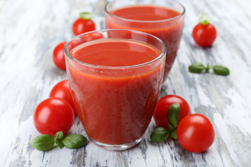 Glasses of tomato juice with vegetables on wooden background