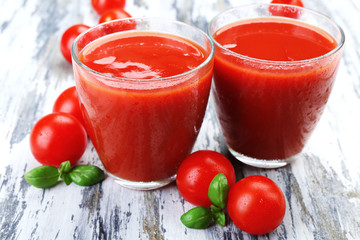 Glasses of tomato juice with vegetables on wooden background