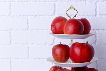 Tasty ripe apples on serving tray on brick wall background