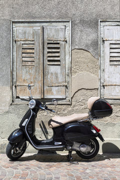 Vintage motor scooter in front of an old facade with weathered shutters