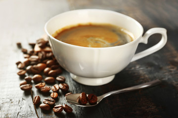 Cup of coffee with beans on table, closeup