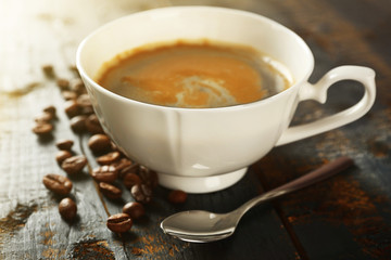 Cup of coffee with beans on table, closeup