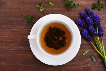 Cup of herbal tea with flowers on wooden table, top view