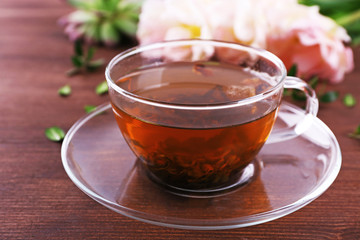 Cup of herbal tea with tulips on wooden table, closeup