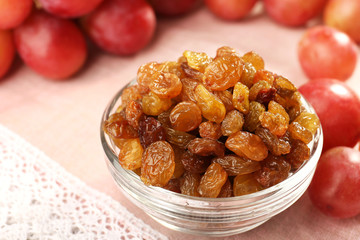 Raisins in bowl with grapes on table close up