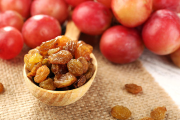 Raisins in wooden spoon with grapes on table close up