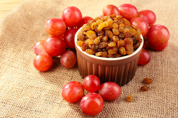 Raisins in bowl with grapes on table close up