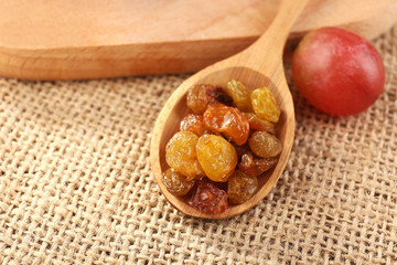 Raisins in wooden spoon with grapes on table close up
