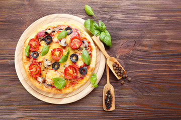 Tasty pizza with vegetables and basil on wooden background