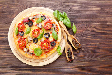 Tasty pizza with vegetables and basil on wooden background