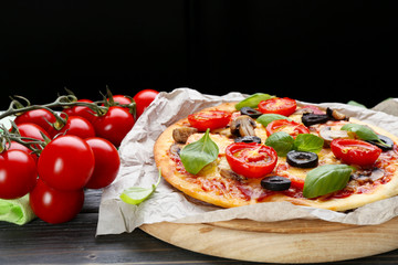 Tasty pizza with vegetables and basil on black background