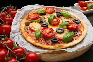 Tasty pizza with vegetables and basil on table close up