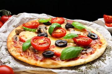 Tasty pizza with vegetables and basil on table close up
