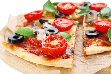Tasty pizza with vegetables and basil on cutting board close up