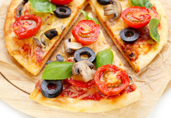 Tasty pizza with vegetables and basil on cutting board close up