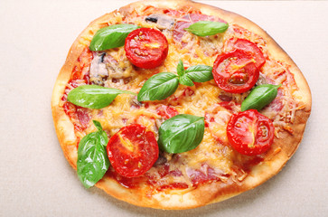 Tasty pizza with vegetables and basil in cardboard box close up